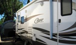 This is a 1/2 Ton Series with the Polar Package Plus, has an enclosed underbelly with heated and enclosed tanks and dump valves, an electric awning with manual override, one power slide, cherry cabinets through out, a walk-around queen size bed and sleeps