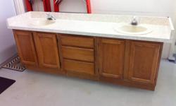 7 foot solid oak vanity. &nbsp;Includes formica countertop with 2 almond sinks and Moen faucets. &nbsp;Double doors on either side of 3 drawers. &nbsp;Excellent condition.