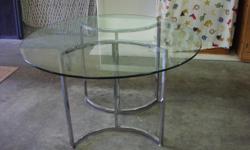 Beautiful, heavy glass-topped table with silver-colored base in fantastic condition. The glass is very thick and heavy on this piece. Table measures 28 3/4 inches tall while on the stand and the glass table top measures 46 inches around. No chairs are