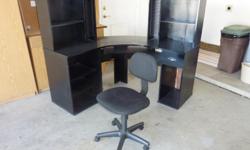 corner computer desk, black in color and office type chair black in color.