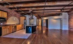 This is a true loft home with dramatic high, beamed ceilings, exposed brick walls, original fir plank floors, and over-sized windows with eastern and southern exposures. The airy, open floor plan, features a kitchen with granite counter tops, stainless