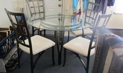 Very nice Asian-style table with four chairs. Round glass table on metal base, with four chairs with metal frame and velour-like padded seats. In great condition overall. One chair has a small spot on it, as shown in photo three.