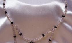 Hand made secured by a silver leaver clasp measures 15 1/2 inches strand hanging resulting in a 1 inch loop. White frosted, black, heart shaped cameo accented in the center of loop. Strand is composed of clear & smoke bicone with black beads. Any