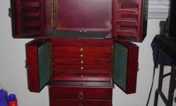 Jewelry Armoire - Has a cherry finish - top pull open doors open for necklaces and earrings to hang on 10 swing out racks and hooks on the back of case. The bottom of first tier holds about 25 to 30 rings. The second tier has 6 hooks on the doors and 5