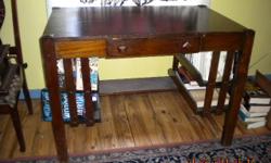 This table is sturdy and has a mission style with some slight veneer damage to the top. There are four library shelves, two on each side of the table.
