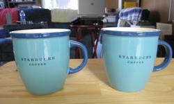 Cute pair of blue Starbucks coffee mugs. Light blue with dark blue trim around the rim. Each says Starbucks Coffee on front of coffee and Starbucks down the rim.