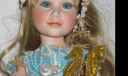 Serena is a porcelain doll from the Danbury Mint. She is a mermaid, approximately 14 inches tall and seated on a rock. She has blonde hair and blue eyes and is holding a sea horse lyre. She was sculpted by Judy Belle and is serial number A826. She comes